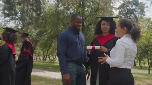 Positive African Female Graduate Communicating with University Professors at Graduation Day