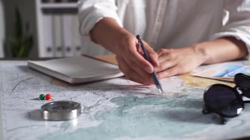 Person Planning Trip with Map and Compass