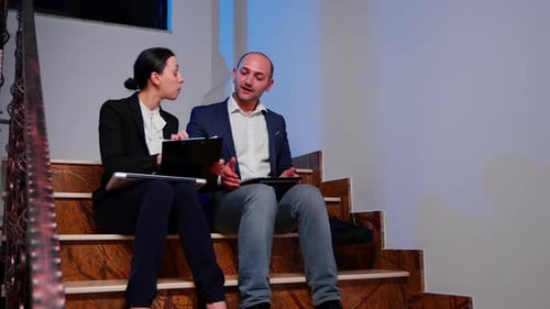 Colleagues Working on Staircase with Tablet and Clipboard