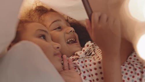 Mother and Child Smiling Under Sheet With Mobile Phone