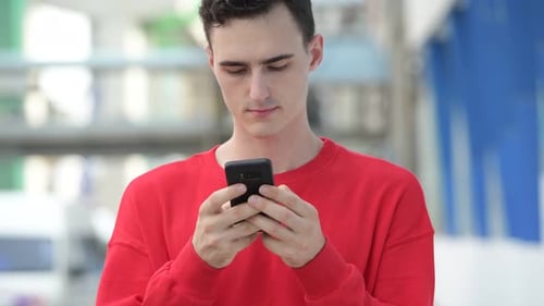 Smiling Young Adult Using Smartphone in City