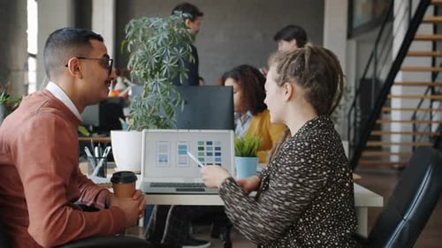 Arab Man and Caucasian Woman Discussing Smartphone Application Development Using Computer in Office