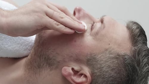Man Cleans His Face with Cotton Pads