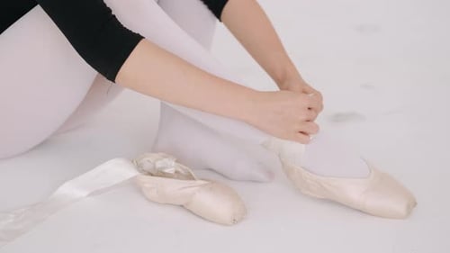 Elegant Ballerina Tying Pointe Shoe Ribbons in Studio