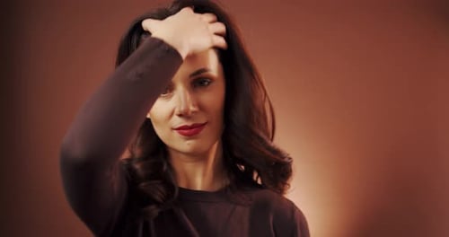 Beautiful Woman Poses in Studio on Brown Background