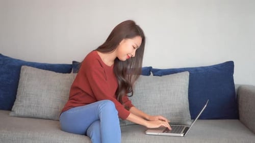 Woman Typing on Laptop While Sitting on Couch