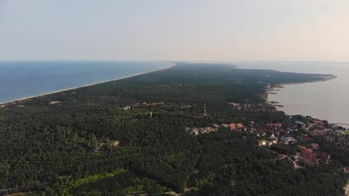 AERIAL: flying backwards and revealing little fisherman village near the sea shore on forest edge