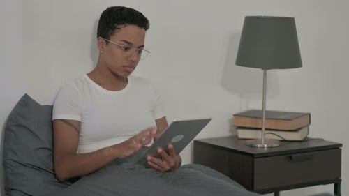 Woman Using Tablet in Bed in her Bedroom