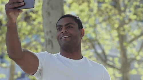 Smiling Man Taking Selfie Outdoors in Daylight