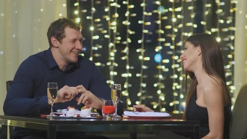 Smiling Couple Spends Evening Time Sitting on Date in Restaurant
