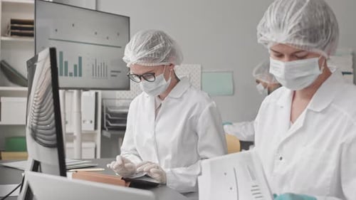 Lab Workers Analyzing Data Wearing Masks and Hairnets