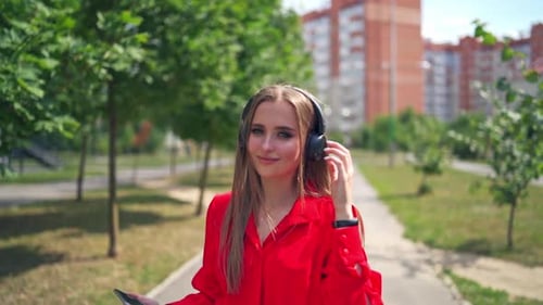 Lovely girl outdoors. Portrait of a young woman with headphones.