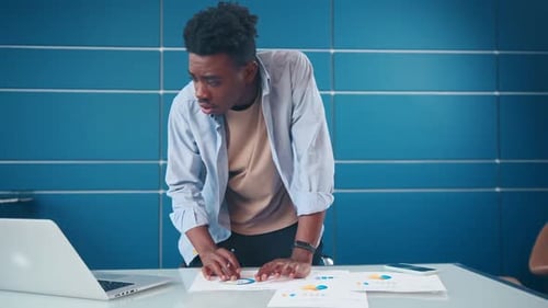 African American Man Stands at Office Desk Taking Notes Planning Agenda