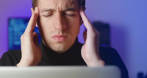 Stressed man with headache working late at computer