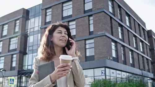 Smiling Woman Talking on Phone While Walking in City
