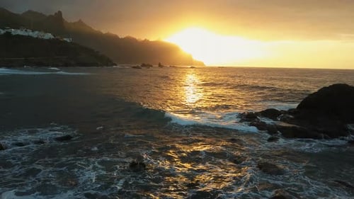 Luftaufnahme. Meereswellen stürzen auf Felsen und sprühen in wunderschönem Sonnenuntergangslicht in der Nähe von Benijo Beach in