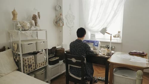 Vista trasera de una mujer sentada en su sala de trabajo
