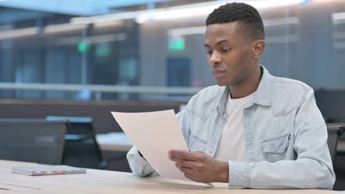 African Man Reading Documents in Office