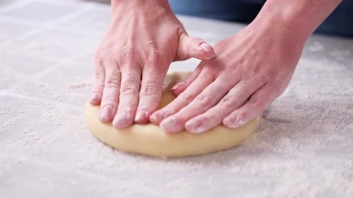 Hands Kneading Dough on Floured Surface