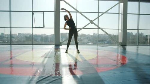 Beautiful Young Sportswoman Wearing Trendy Leggings and Top Doing Warmup in Gym