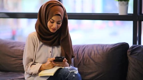 Woman on Couch Texts with Book Open