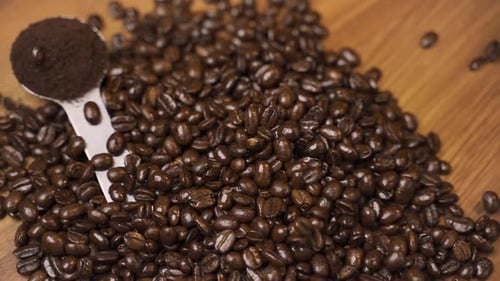 Roasted coffee beans falling onto a wooden surface.
