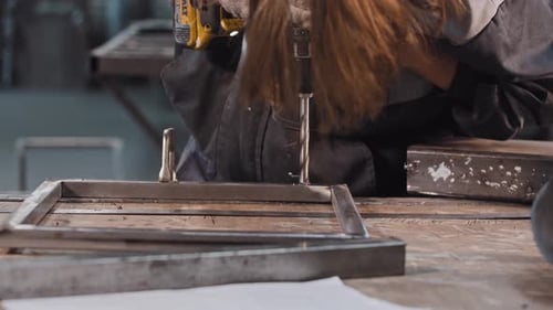 Young Man Working at the Manufacturing Plant Drilling Holes in Metal Construction