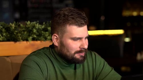 a Brutal Bearded Man Is Sitting in a Cafe and Working on a Laptop