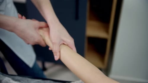 Massage - Masseurin knetet die Hand einer Frau von der Schulter bis zum Handgelenk