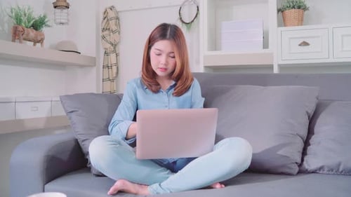Young Woman Using Laptop on Couch at Home