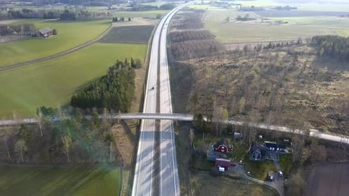 Freeway road with moving cars between green fields.