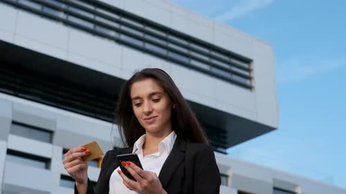 Woman Uses Phone and Credit Card in City