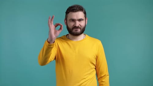 Hübscher Mann in gelber Kleidung zeigt Okay Ok Geste