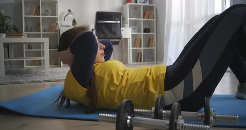 Young Lady Is Training Abdominal Muscles Lifting Body To Knees Lying on Floor Workout at Home Sporty