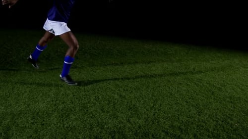 Soccer Player Kicking Ball at Night