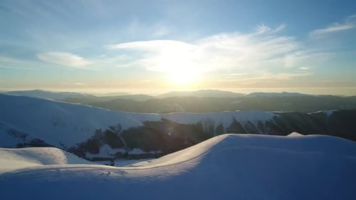 Flight Over the Snowy Mountains Illuminated By the Evening Sun