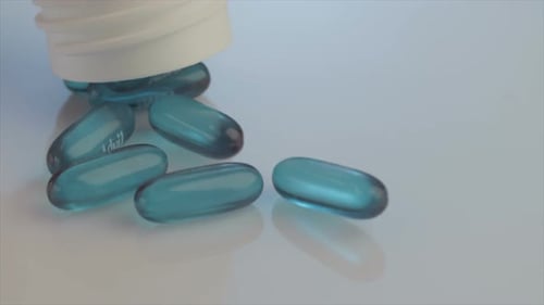 Blue Gel Capsules Pouring From Bottle