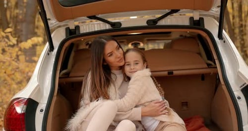 Mother and Daughter Hugging in Car Trunk