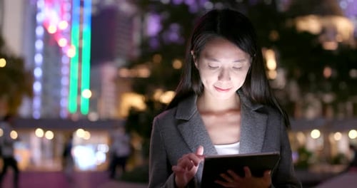 Woman Using Tablet at Night in City
