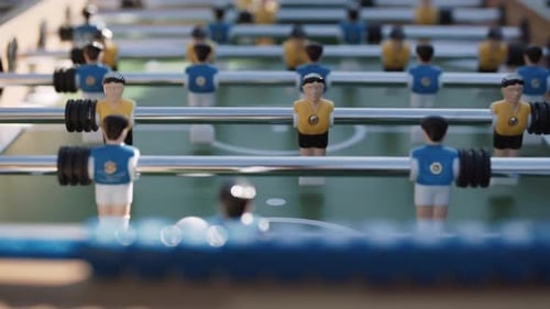 Figurines of Blue and Yellow Players Beat Off White Ball on Kicker Field