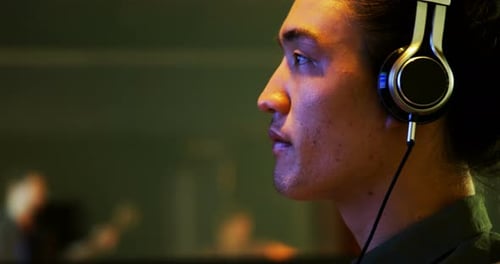 Male audio engineer listening to headphones while mixing sound