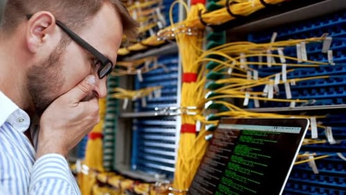 Man Working on Laptop in Server Room