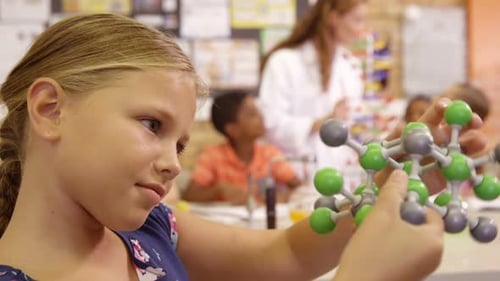 Young Girl Examining Molecular Model in Science Classroom