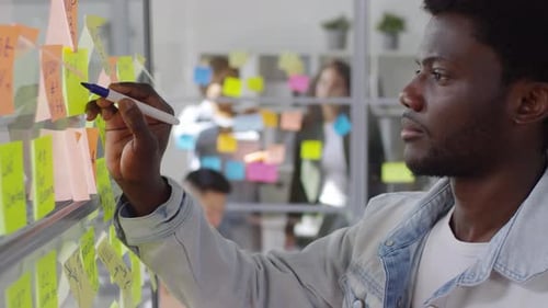 African Businessman Writing on Sticky Notes in Office
