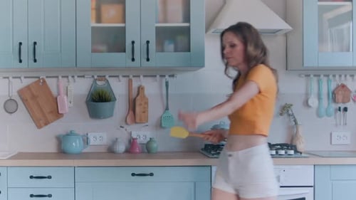 Happy Woman Dancing in Sunlit Kitchen