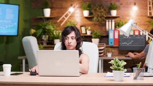 Excited Woman Working on Laptop in Green Office