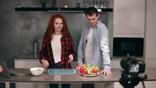 Junges Paar kocht in ungezwungener Atmosphäre zusammen und nimmt Food-Blog auf Video auf der Kamera im Loft Grey auf