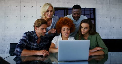 Team Collaborating Around Laptop in Modern Office