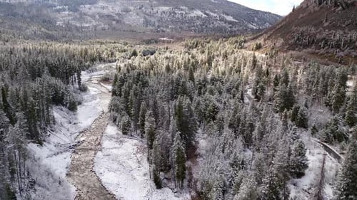Aerial view flying over river flowing through snow covered landscape