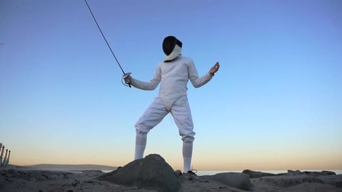 A man and woman fencing on the beach